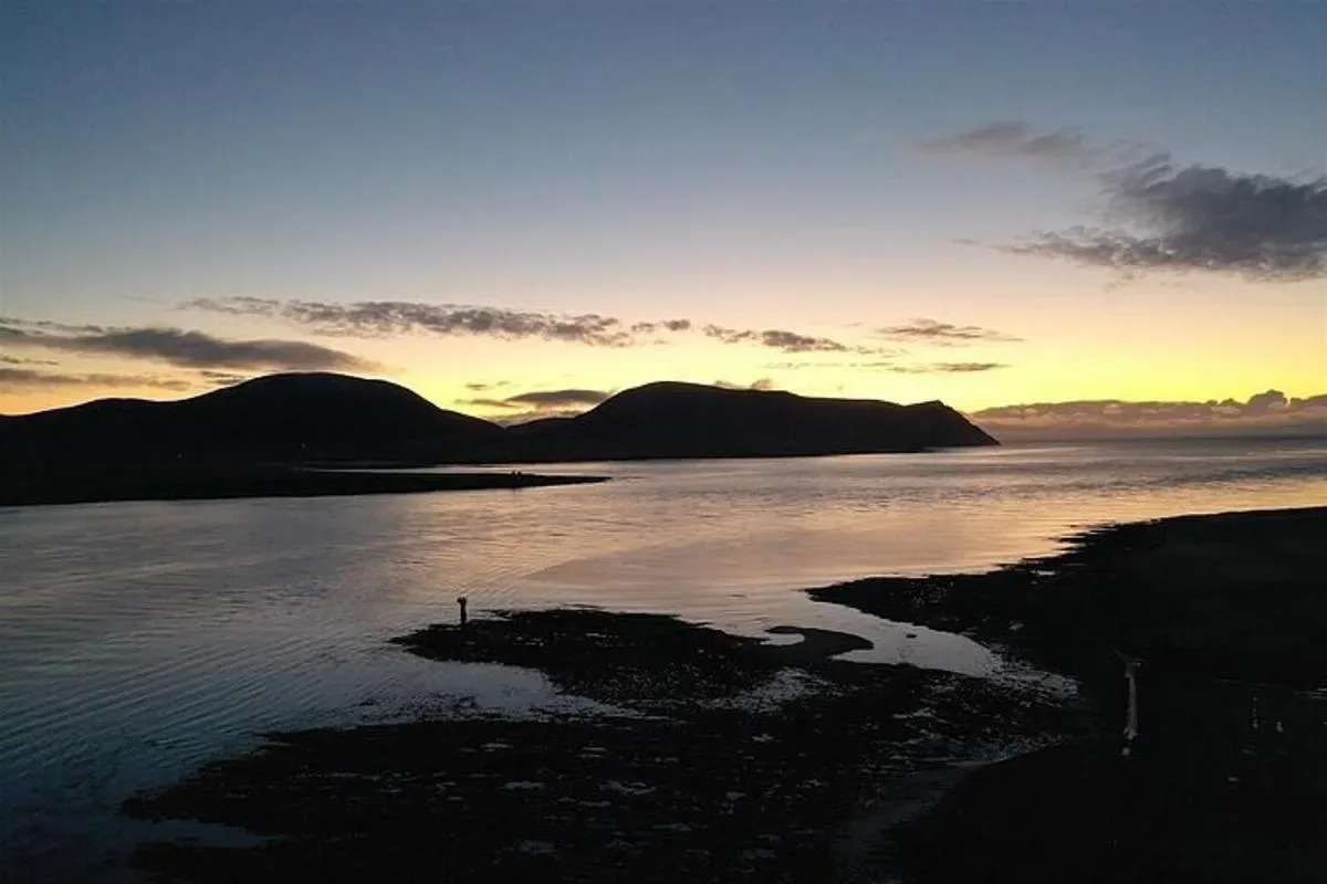 a sunset over a body of water with mountains