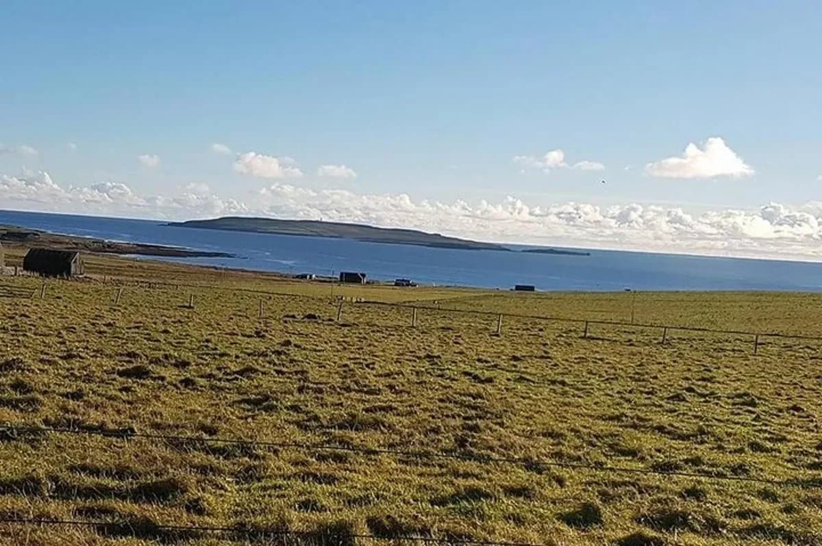 a field with a fence in front of the water