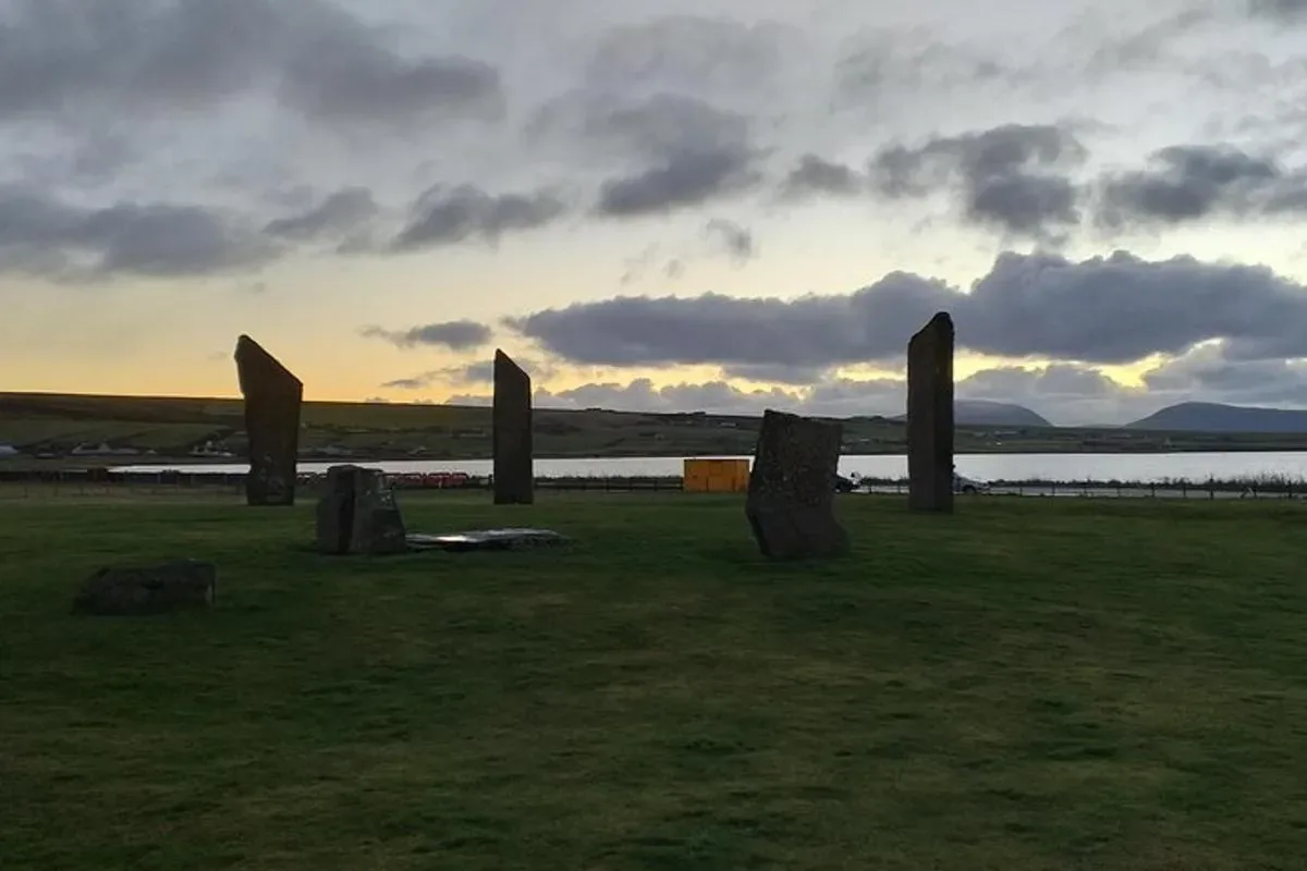 a group of stone posts in a field with a body of water