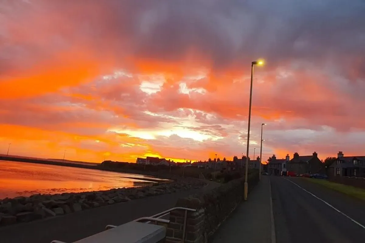 a sunset over the ocean with a street light