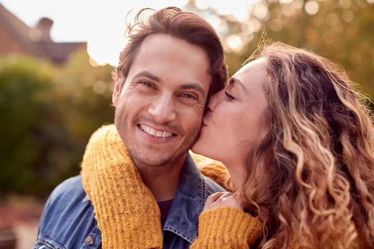 a man and a woman are getting a kiss