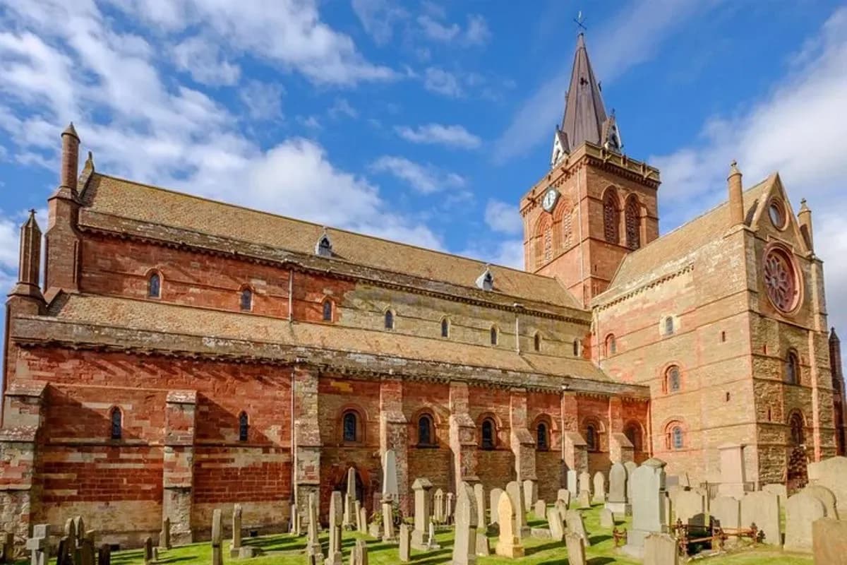 a large brick building with a clock tower and a cemetery