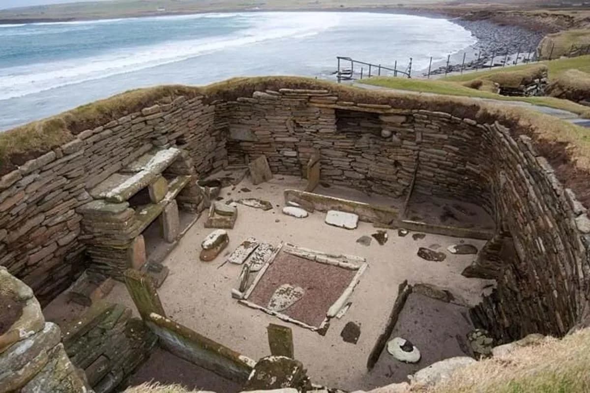 an old stone building with the ocean in the background