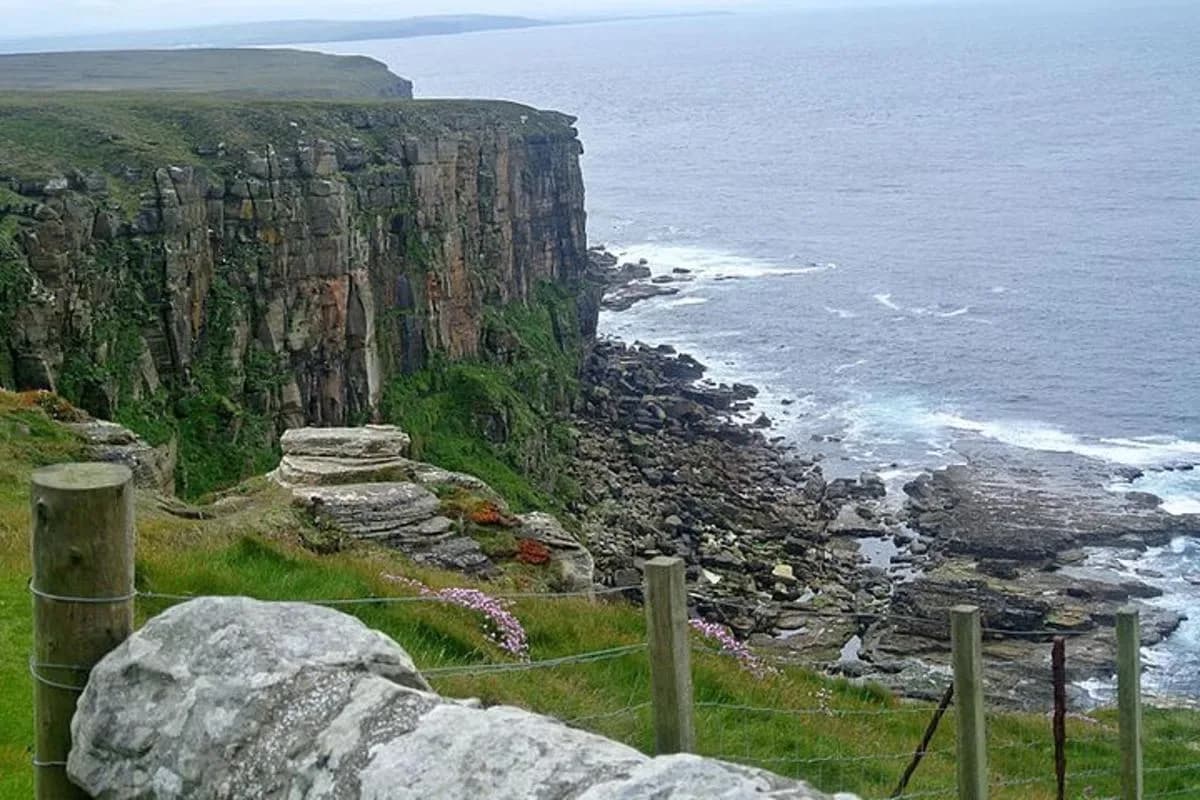 a fence on top of a cliff near the ocean