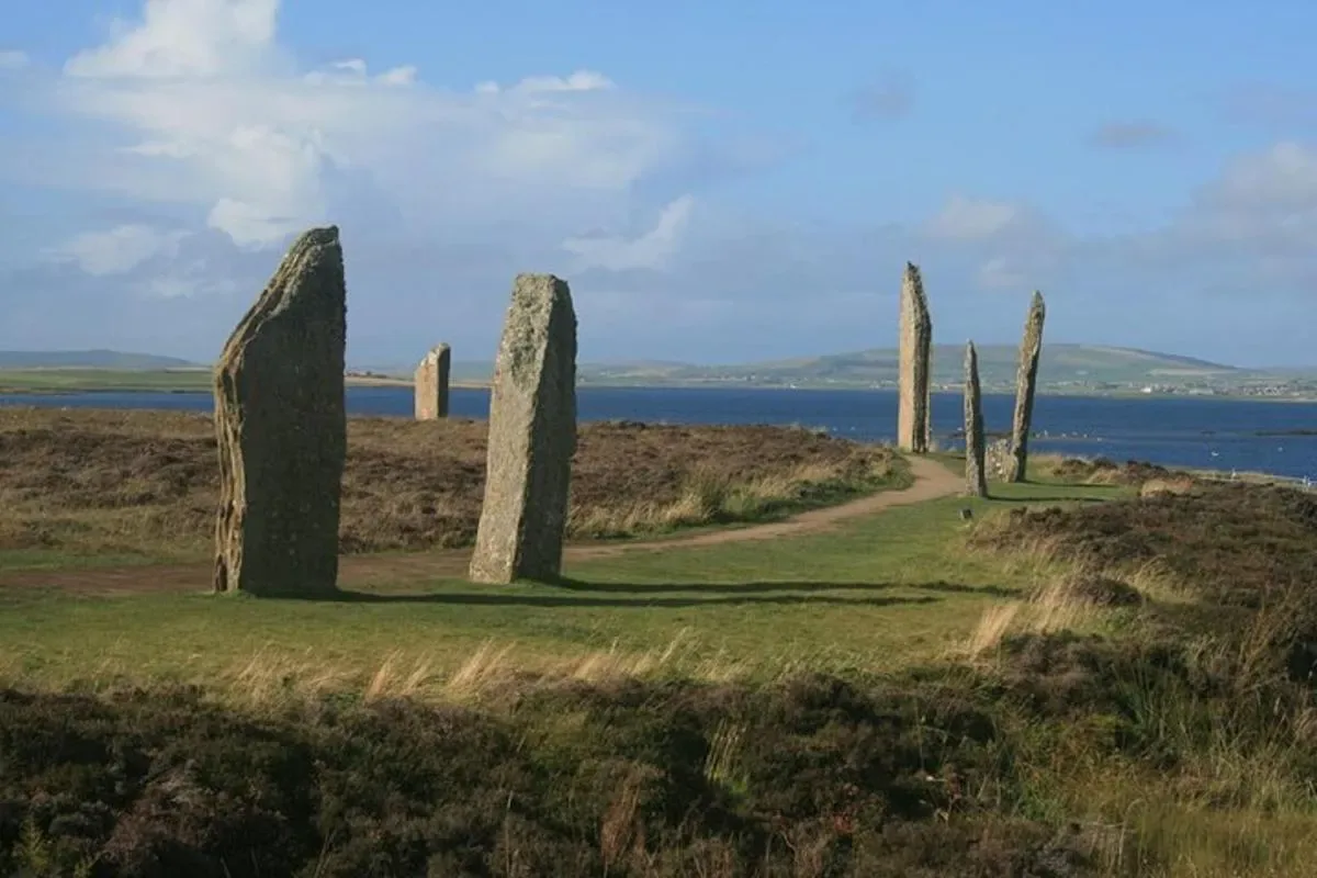 a group of stone pillars on a field with a road