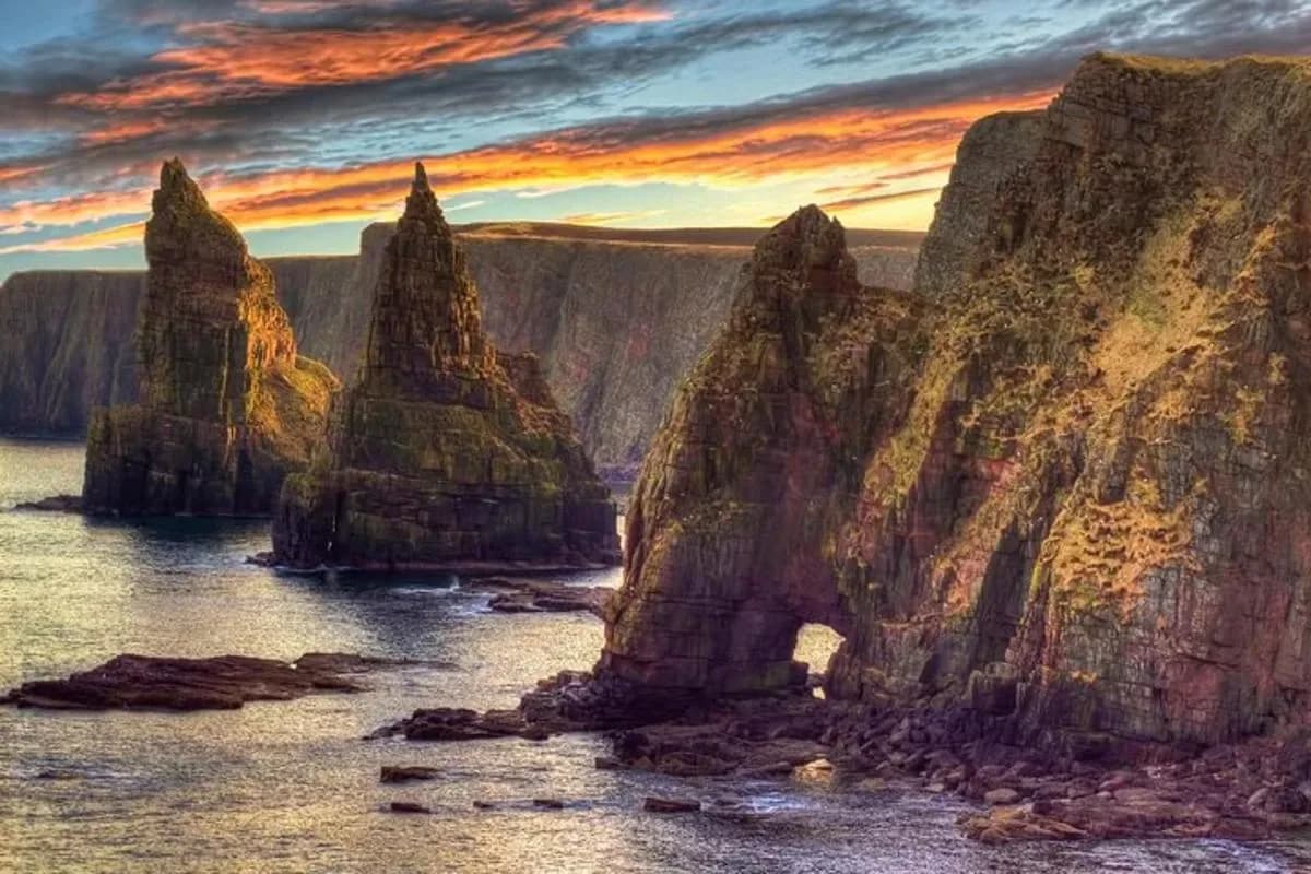 a group of large rocks in the water at sunset