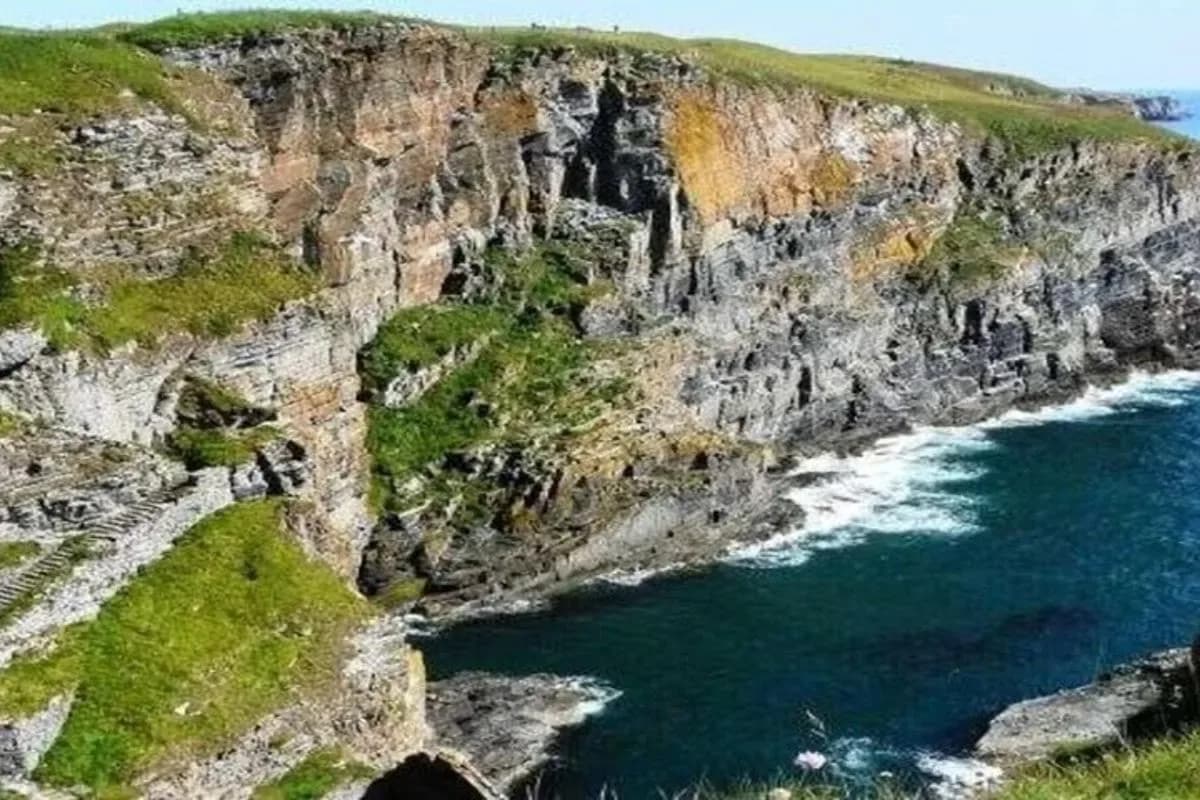 an aerial view of a rocky cliff next to the ocean