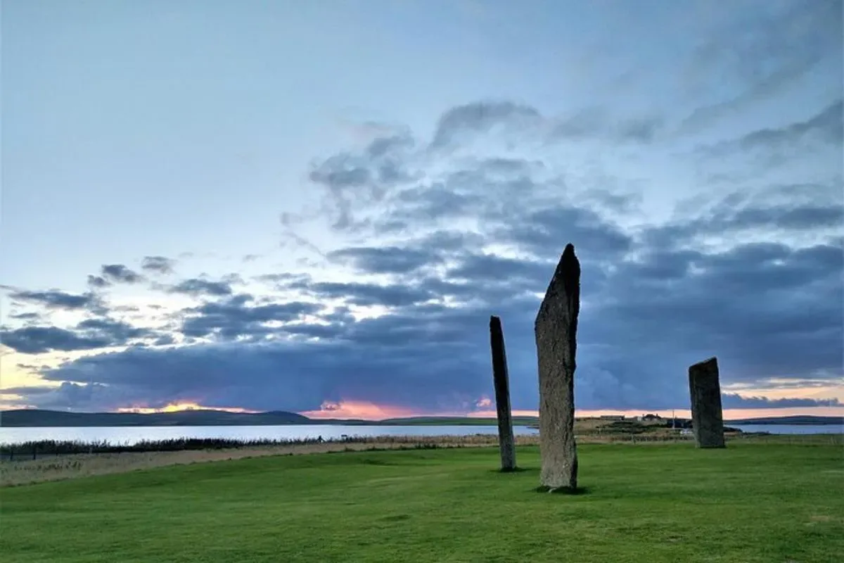 a group of stone pillars in a field with a cloudy sky
